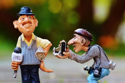 Photo de 2 figurines représentant un photofraphe et un journaliste avec un micro